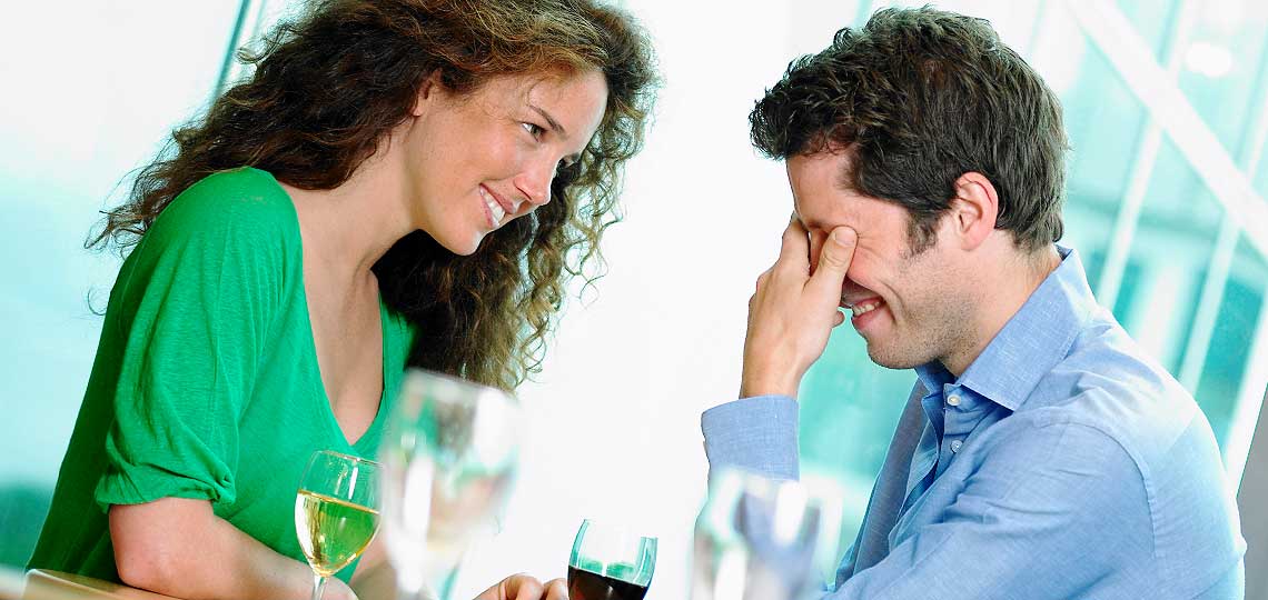 Couple riant avec verres de vin.
