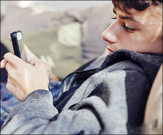 Jeune homme (ado) se cache pour regarder son téléphone
