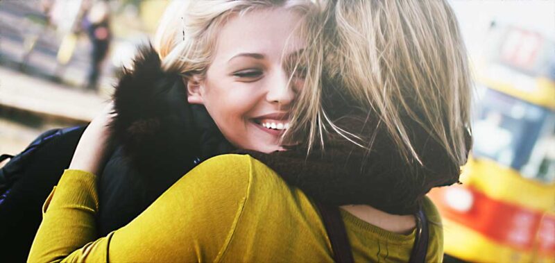 Deux amies s'embrassant chaleureusement en public.
