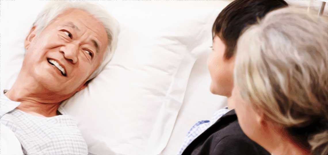 Homme âgé souriant à sa famille, dans un lit d'hôpital.