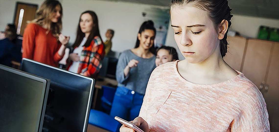 Jeune fille regardant son téléphone en classe, elle est moquée par ses camarades.